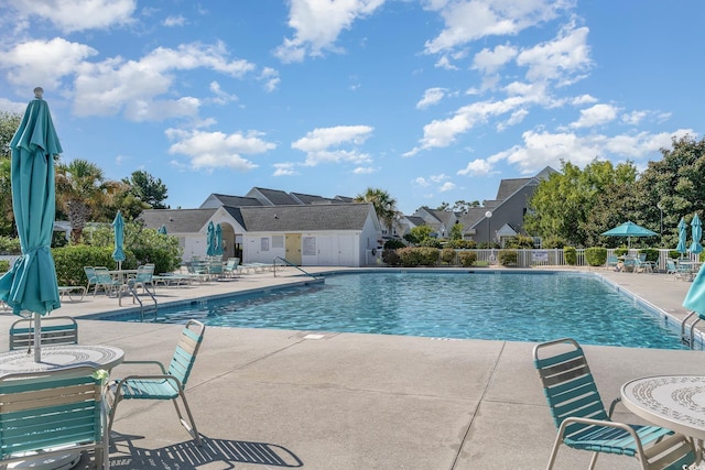 community pool featuring a patio area, fence, and a residential view