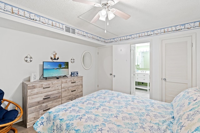 1310 N Waccamaw Dr Unit 204, Garden City Beach, SC 29576 - bedroom featuring a textured ceiling, ensuite bath, ceiling fan, a sink, and wood finished floors