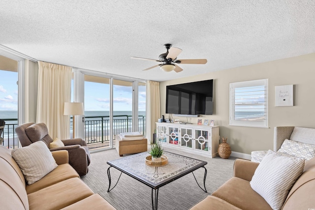 3805 S Ocean Blvd # 503, North Myrtle Beach, SC 29582 - living room with a textured ceiling, a ceiling fan, expansive windows, carpet floors, and baseboards