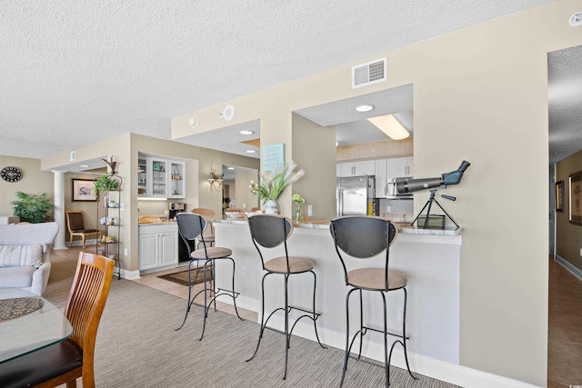 3805 S Ocean Blvd # 503, North Myrtle Beach, SC 29582 - kitchen featuring appliances with stainless steel finishes, white cabinets, a kitchen bar, a peninsula, and light countertops