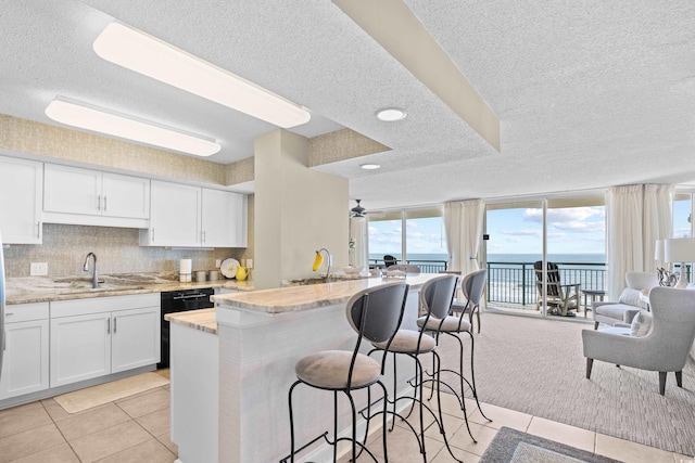 3805 S Ocean Blvd # 503, North Myrtle Beach, SC 29582 - kitchen featuring a sink, a textured ceiling, dishwasher, a breakfast bar, and light tile patterned flooring