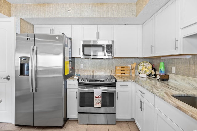 3805 S Ocean Blvd # 503, North Myrtle Beach, SC 29582 - kitchen featuring stainless steel appliances, light tile patterned floors, white cabinetry, light stone counters, and backsplash