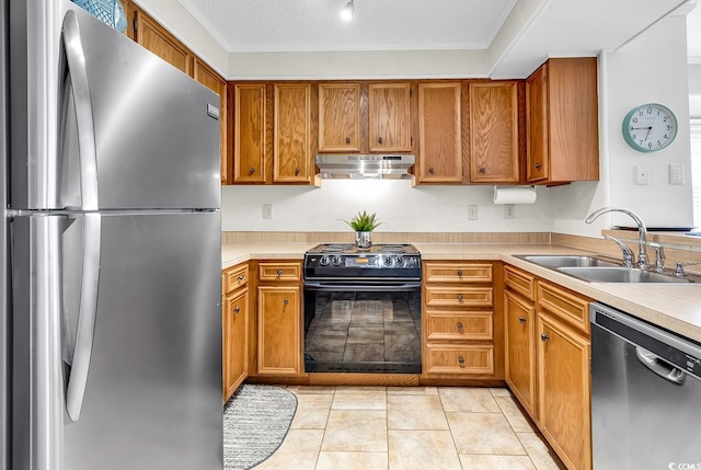 kitchen featuring appliances with stainless steel finishes, a sink, under cabinet range hood, light countertops, and brown cabinets