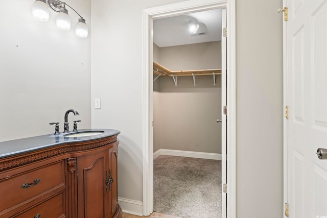 bathroom featuring vanity, baseboards, and a walk in closet