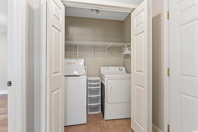 clothes washing area with washer and dryer and light tile patterned floors