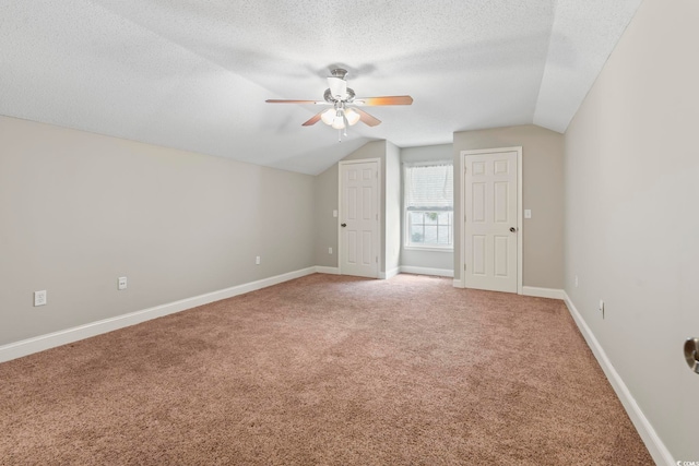 additional living space featuring ceiling fan, vaulted ceiling, light carpet, a textured ceiling, and baseboards