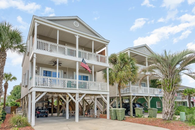 coastal home featuring a carport, a balcony, a ceiling fan, driveway, and a porch