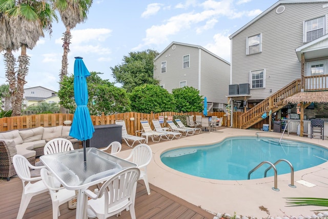 view of swimming pool with a fenced backyard, stairway, a deck, and outdoor dining area