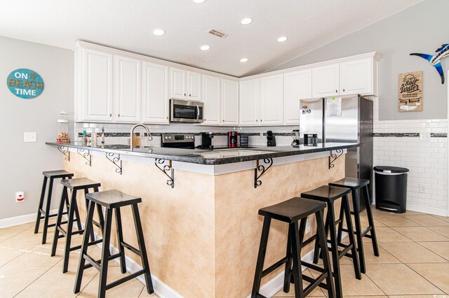 163 Cypress Ave, Murrells Inlet, SC 29576 - kitchen featuring appliances with stainless steel finishes, light tile patterned floors, a peninsula, white cabinets, and lofted ceiling