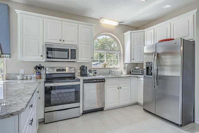 500 23rd Ave S, North Myrtle Beach, SC 29582 - kitchen with stainless steel appliances, white cabinetry, a sink, light stone counters, and a textured ceiling