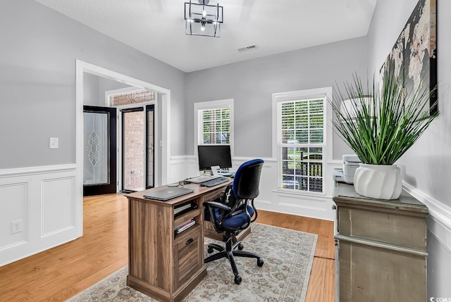 office with wainscoting, light wood-type flooring, and a decorative wall