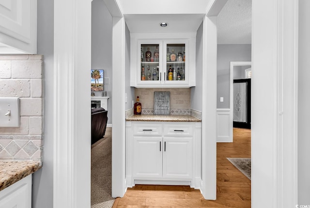 bar area with light wood-type flooring and decorative backsplash