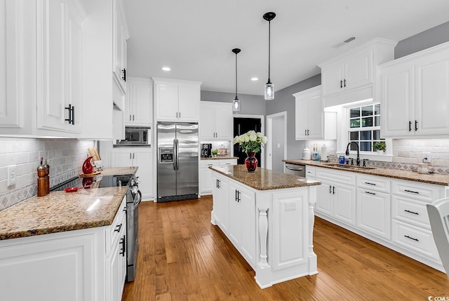 kitchen featuring stainless steel appliances, a sink, recessed lighting, backsplash, and a center island