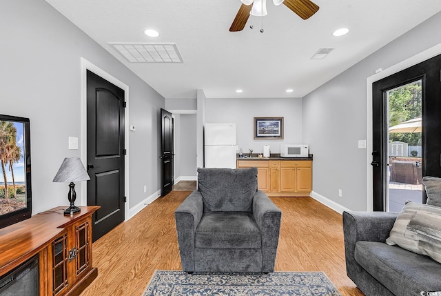 living room featuring light wood finished floors, baseboards, recessed lighting, and a ceiling fan