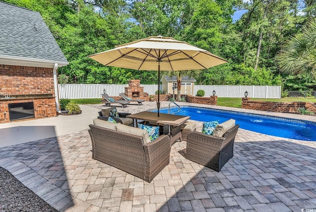 view of pool featuring a patio area, a fenced backyard, an outdoor living space with a fireplace, a shed, and an outbuilding