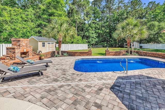 view of pool featuring a storage unit, an outdoor structure, a patio, view of wooded area, and an outdoor brick fireplace