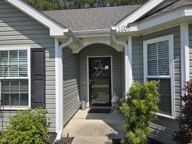 doorway to property with roof with shingles