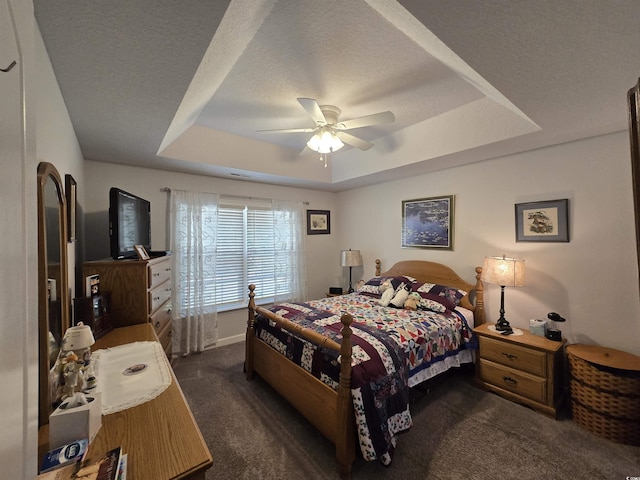 carpeted bedroom with a raised ceiling, ceiling fan, baseboards, and a textured ceiling