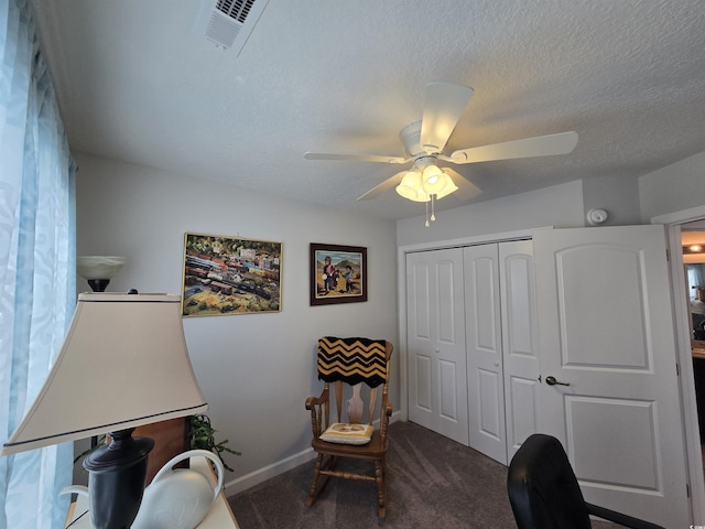 sitting room with dark carpet, a ceiling fan, a textured ceiling, and baseboards