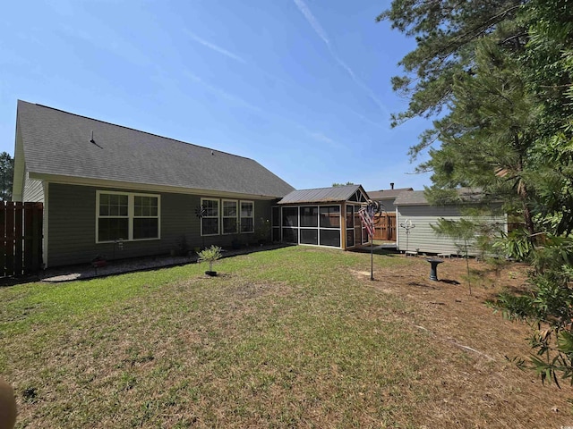 back of house with a sunroom, a storage shed, a shingled roof, and an outdoor structure