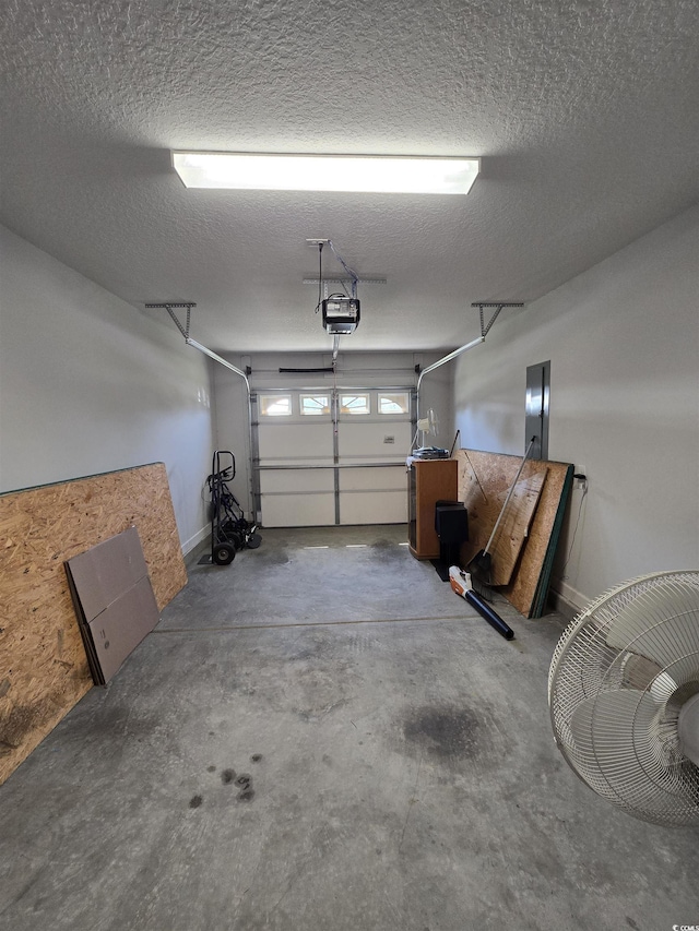 garage featuring a garage door opener, electric panel, and baseboards