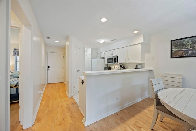 69 Pinehurst Ln Unit 3-F, Pawleys Island, SC 29585 - kitchen with stainless steel microwave, freestanding refrigerator, a peninsula, light countertops, and light wood-style flooring