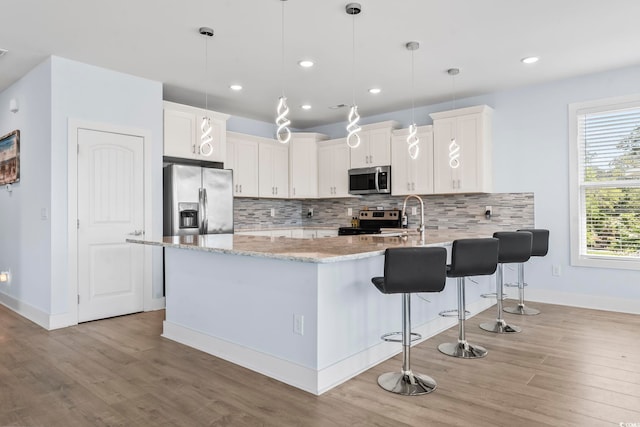 400 Elizabeth Dr, Murrells Inlet, SC 29576 - kitchen featuring stainless steel appliances, a peninsula, light wood finished floors, light stone countertops, and tasteful backsplash