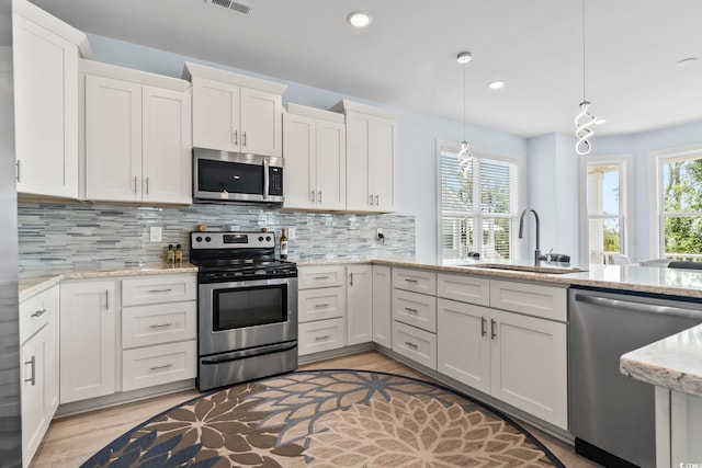 400 Elizabeth Dr, Murrells Inlet, SC 29576 - kitchen with stainless steel appliances, a sink, white cabinetry, light wood-type flooring, and tasteful backsplash