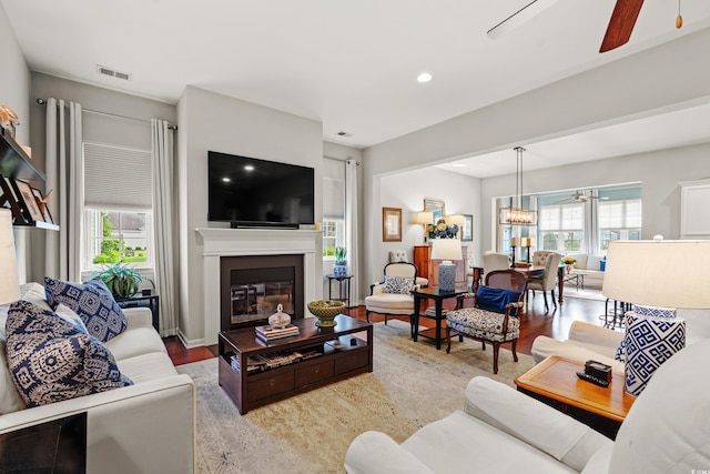 living room with ceiling fan, plenty of natural light, wood finished floors, a glass covered fireplace, and recessed lighting