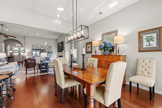 dining space featuring dark wood-style floors, arched walkways, ceiling fan, a chandelier, and recessed lighting