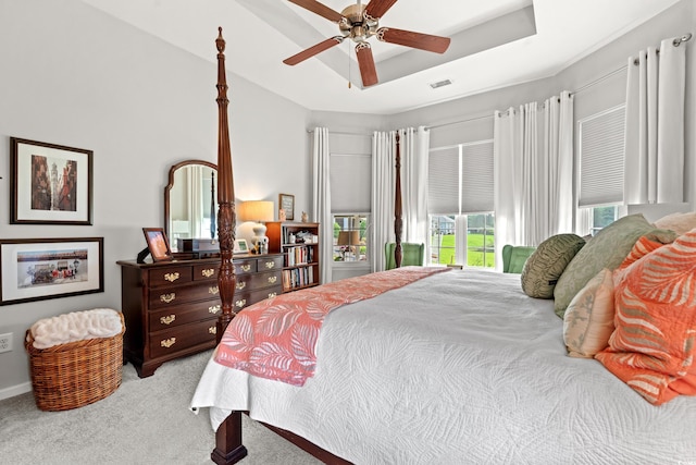 carpeted bedroom featuring a raised ceiling, a ceiling fan, and baseboards