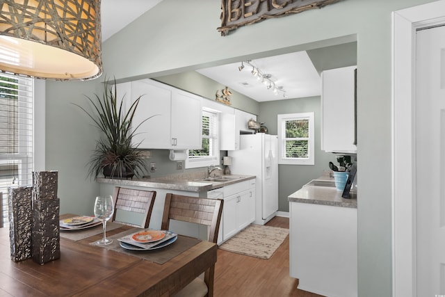 kitchen featuring light wood-style flooring, a sink, white cabinets, lofted ceiling, and white refrigerator with ice dispenser