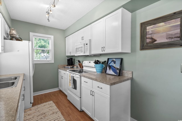 kitchen featuring white appliances, dark wood-style flooring, white cabinets, baseboards, and rail lighting