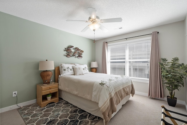 bedroom featuring light colored carpet, baseboards, ceiling fan, and a textured ceiling