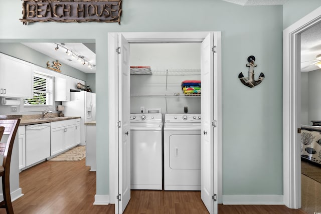 laundry area featuring washing machine and clothes dryer, wood finished floors, and baseboards