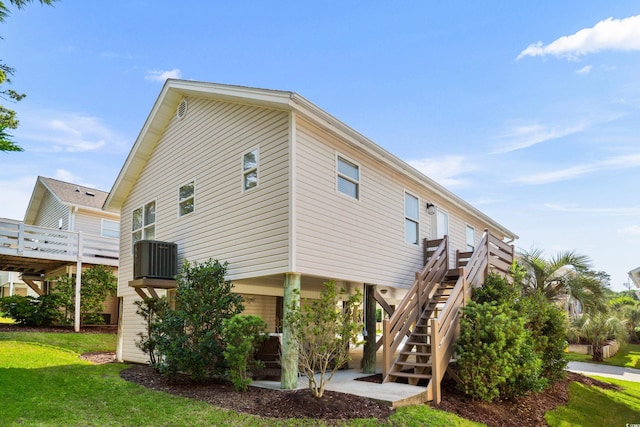 view of side of home with stairs, a yard, central AC, and a wooden deck