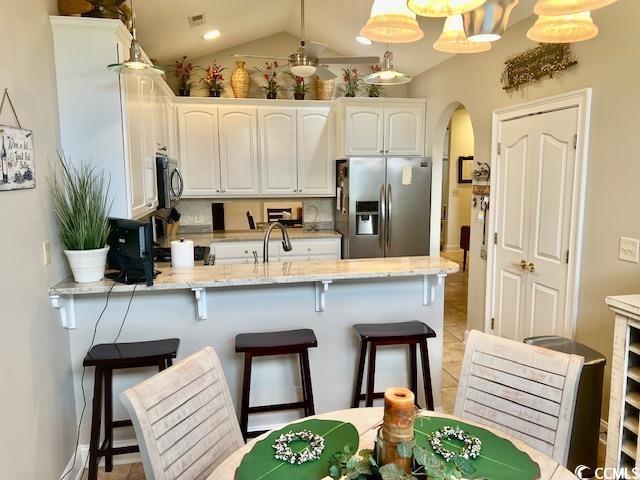 1504 Saint Thomas Cir, Myrtle Beach, SC 29577 - kitchen with stainless steel appliances, a peninsula, arched walkways, white cabinets, and a kitchen bar