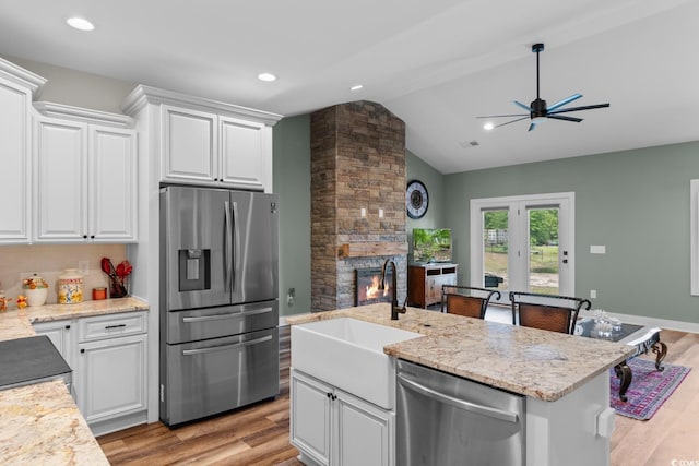 2505 Suzanne Dr, Conway, SC 29526 - kitchen featuring stainless steel appliances, a sink, a stone fireplace, vaulted ceiling, and white cabinetry