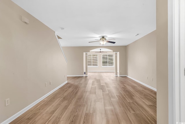 unfurnished living room with ceiling fan, light wood finished floors, and baseboards