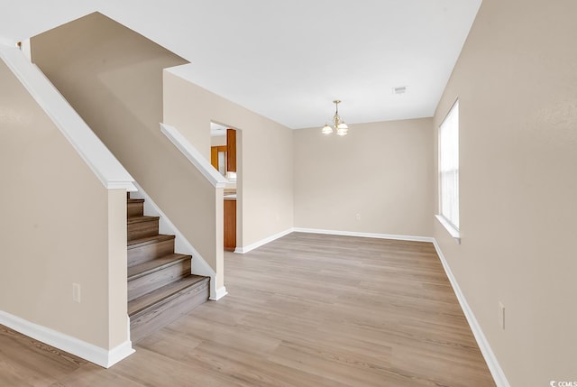 entryway with a chandelier, stairway, light wood-style flooring, and baseboards