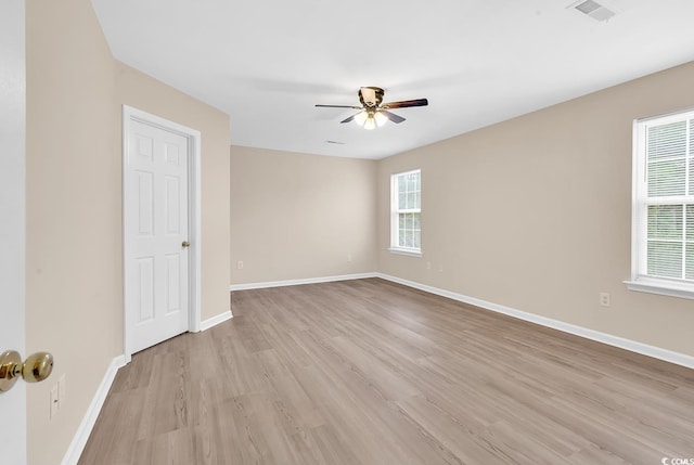 empty room with light wood-type flooring, healthy amount of natural light, ceiling fan, and baseboards