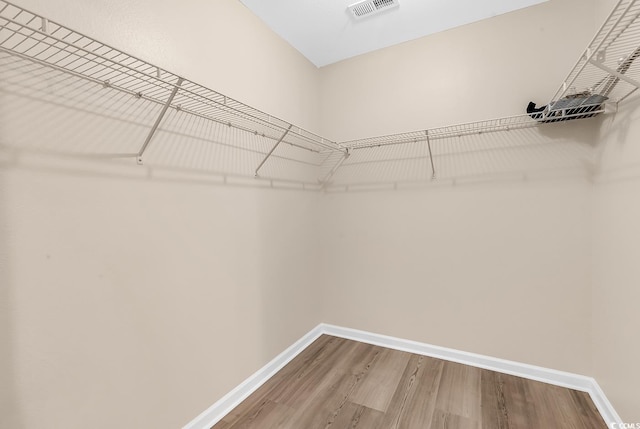 walk in closet with wood finished floors