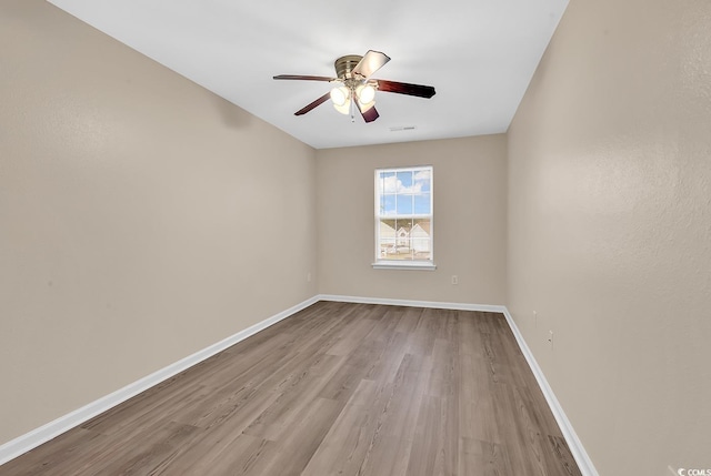 spare room with wood finished floors, ceiling fan, and baseboards