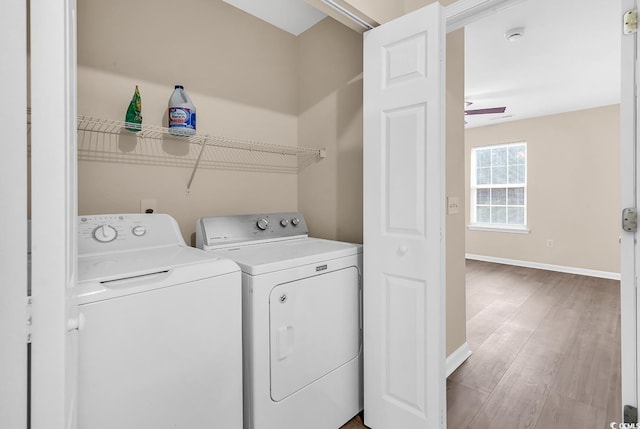 laundry room featuring washing machine and dryer, baseboards, and light wood-style flooring