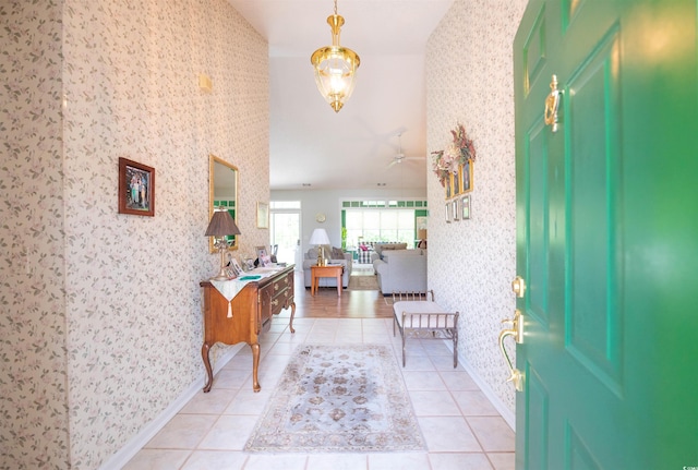 foyer entrance featuring wallpapered walls, a ceiling fan, baseboards, and light tile patterned floors