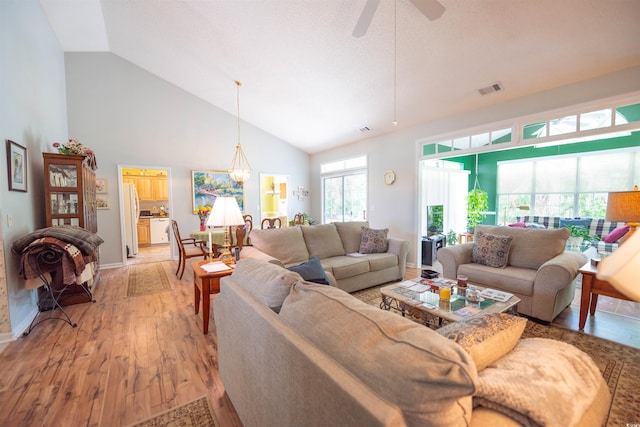 living room with high vaulted ceiling, light wood finished floors, ceiling fan, and baseboards