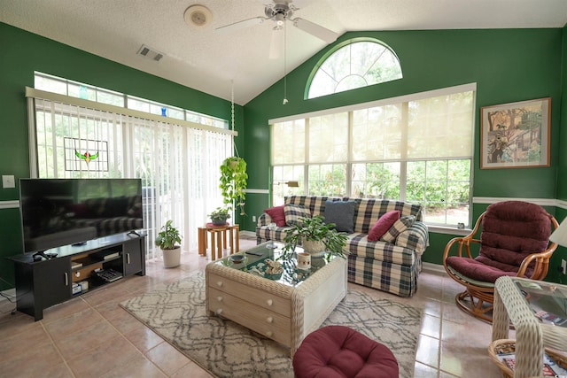 living room featuring healthy amount of natural light, vaulted ceiling, a ceiling fan, tile patterned floors, and a textured ceiling