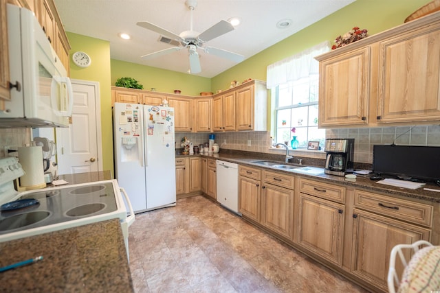 kitchen featuring white appliances, a sink, decorative backsplash, ceiling fan, and dark stone counters