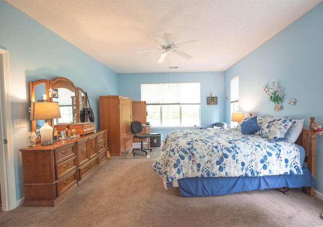 carpeted bedroom with a ceiling fan and a desk