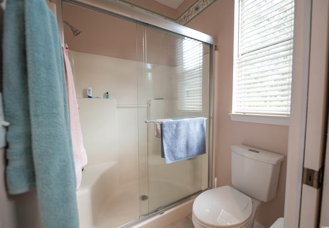 bathroom featuring toilet, a stall shower, and plenty of natural light